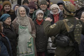 Des civils se réjouissent avec un soldat ukrainien alors qu'un convoi de véhicules militaires et d'aide arrive à Boutcha, faubourg de Kiev auparavant occupé par les troupes russes.